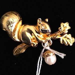 Oggie design squirrel with pearl type accorn on a branch.